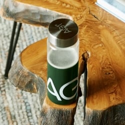 Water bottle full of Athletic Greens on a wood table.