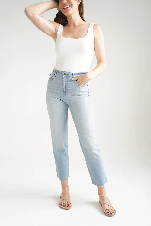 Women model wearing light wash jeans, sandals and a white tank top | discount codes