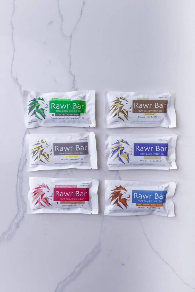 Rawr Bars protein bar including flavors of double dark chocolate and mint, cookie dough, lemon poppy, peanut butter, dark chocolate and strawberry, and dark chocolate and peanut butter.