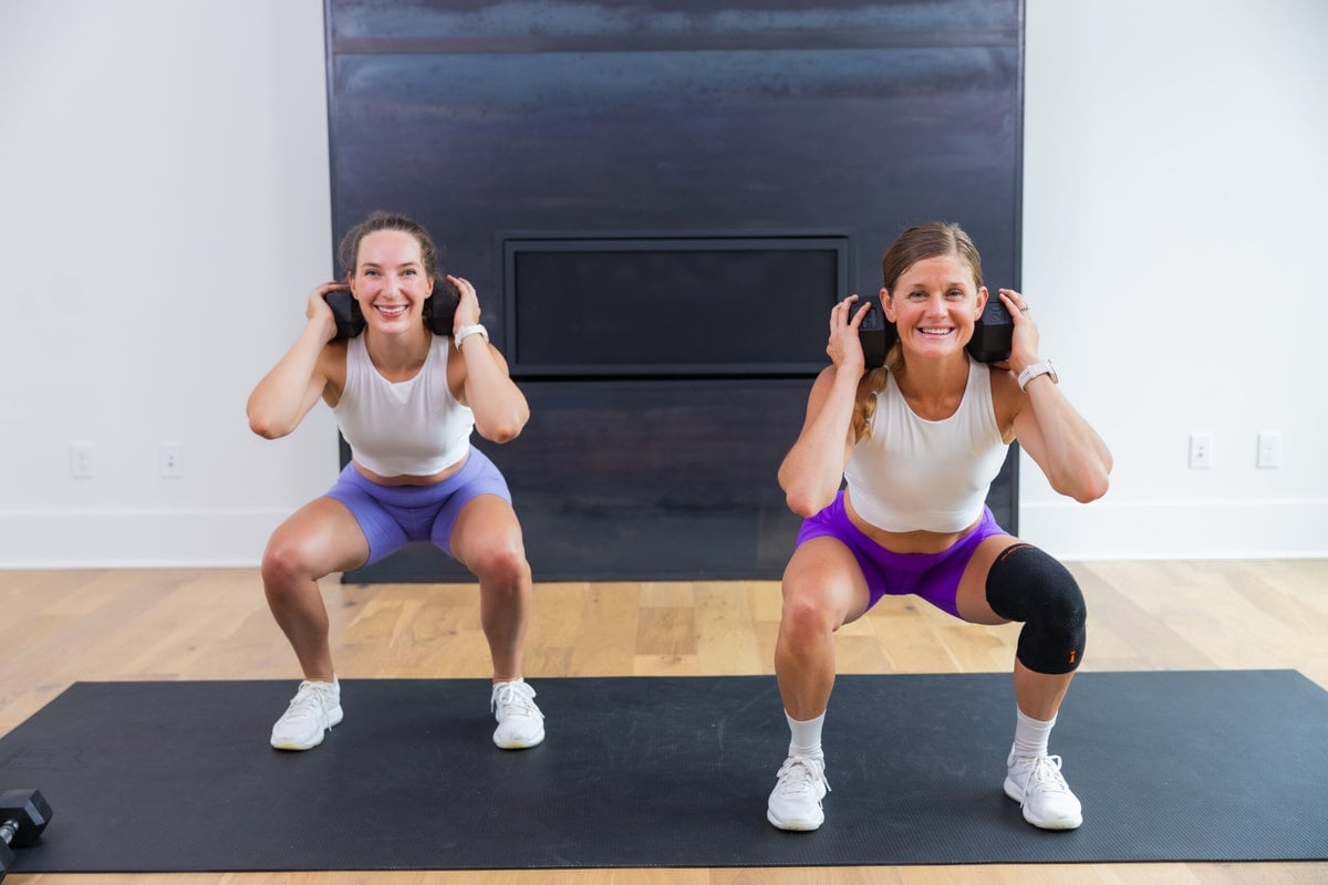 two women performing back squats as example of compound leg exercises
