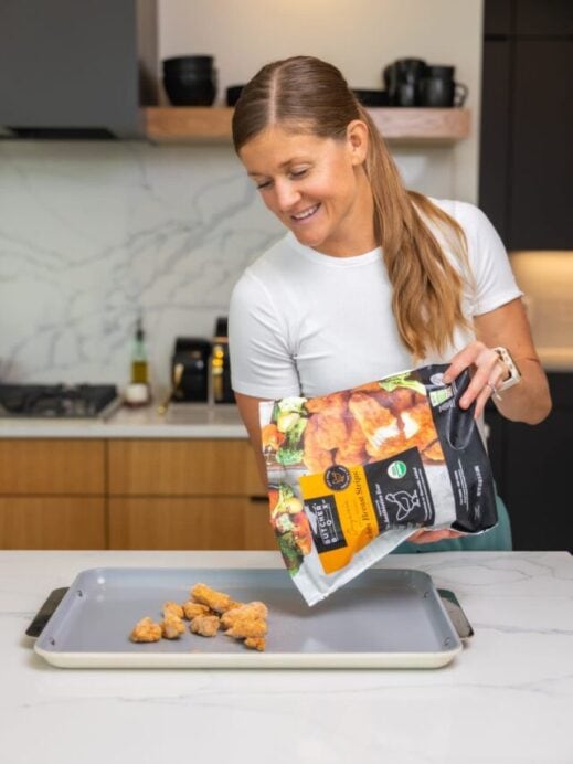 Woman dumping ButcherBox chicken nuggets onto a Caraway sheet pan