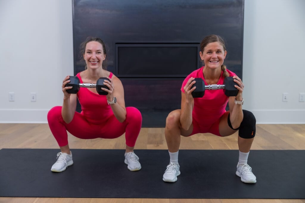 two women performing a low squat as part of 15-minute workout