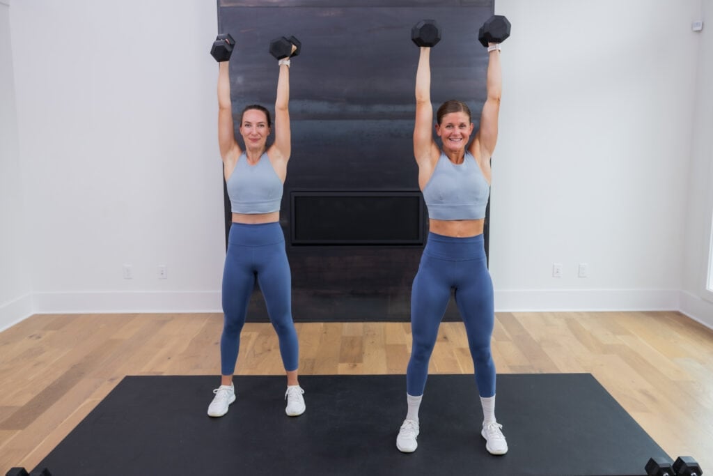 two women performing an overhead press with dumbbells in a full body workout