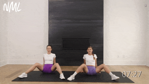 two women performing internal hip rotations as example hip mobility exercises