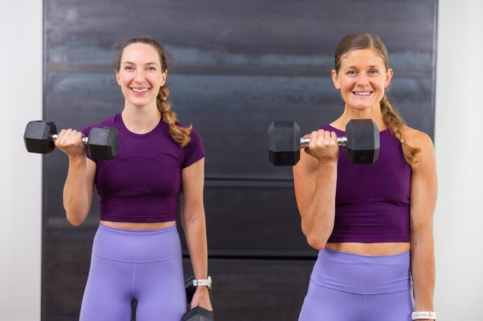 two women performing a standing bicep curl as part of beginner dumbbell workout