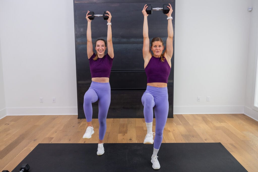 two women performing a standing dumbbell overhead press as part of beginner dumbbell workout