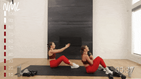 two women performing dumbbell sit ups as part of burpee workout