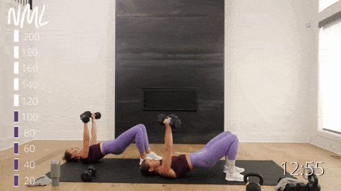 two women performing a glute bridge and chest press with dumbbells in an EMOM workout