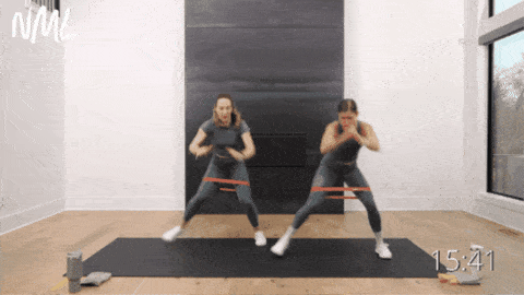 two women performing lateral shuffles with resistance band