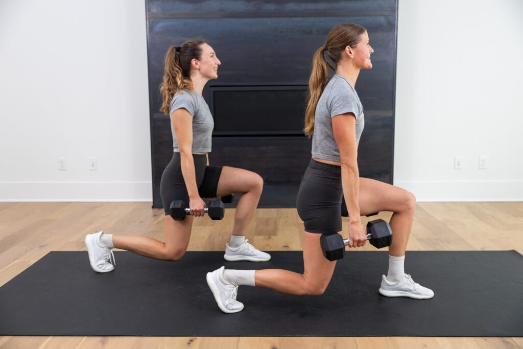two women performing a lunge hold with dumbbells in a squat workout