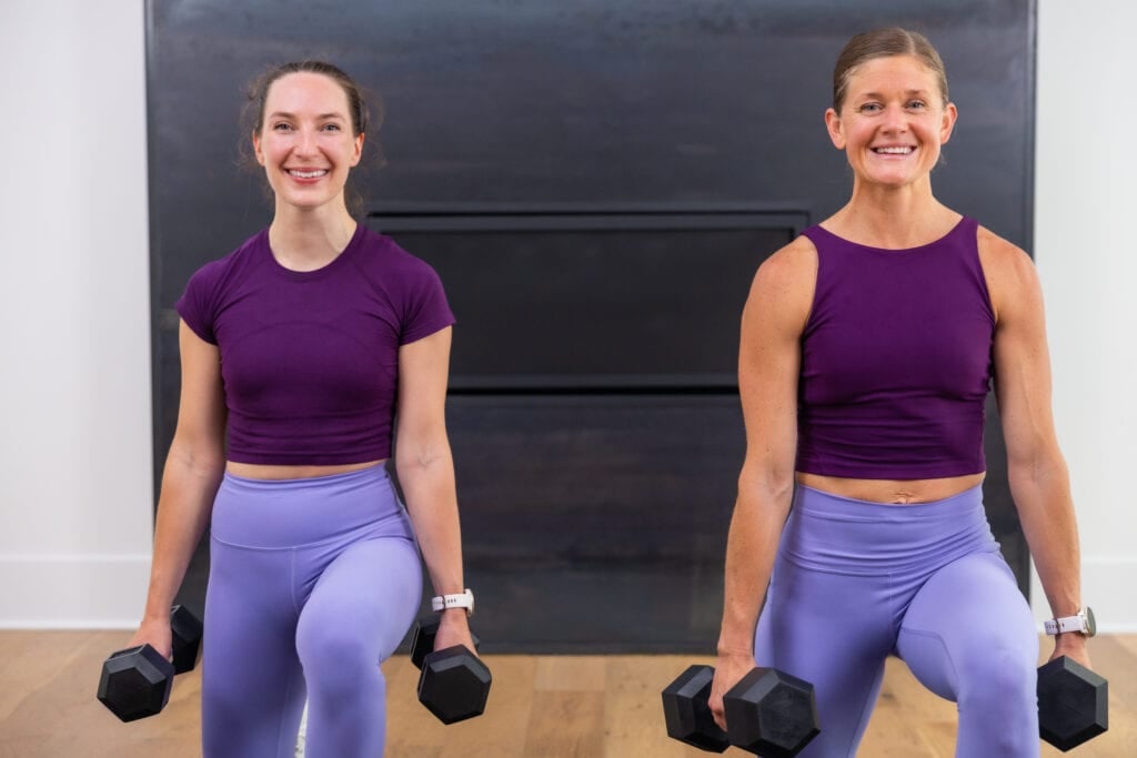 two women performing a reverse lunge with dumbbells in a total body workout
