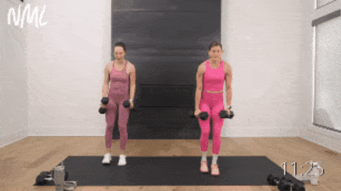 two women performing alternating reverse lunges with a lat raise 