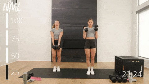 two women performing side to side squat cleans in a dumbbell workout