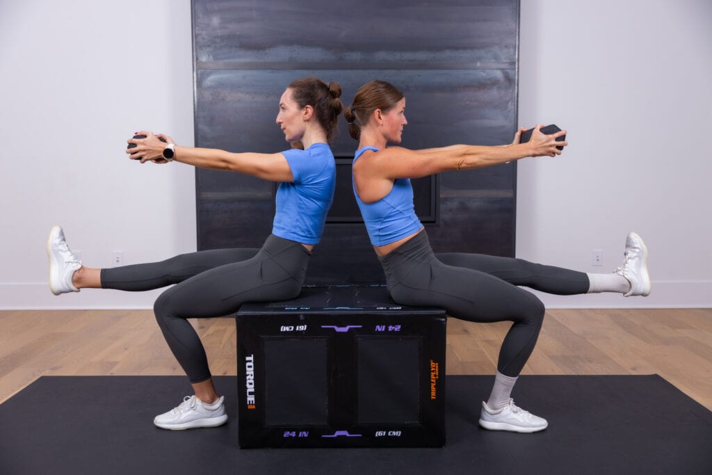 two women performing a single leg squat and dumbbell press out in a full body workout