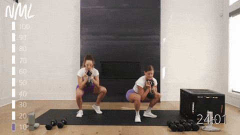 two women performing L stance goblet squats in a dumbbell leg workout