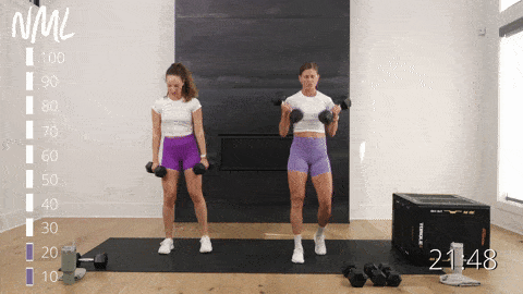 two women performing a staggered deadlift and clean and front squat in a leg workout with dumbbells
