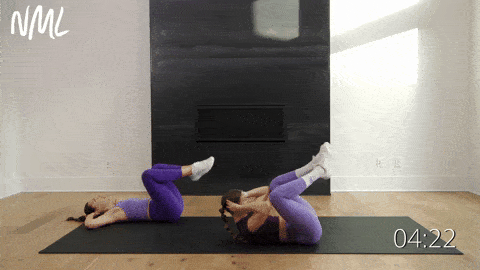 two women performing butterfly crunches in an ab workout