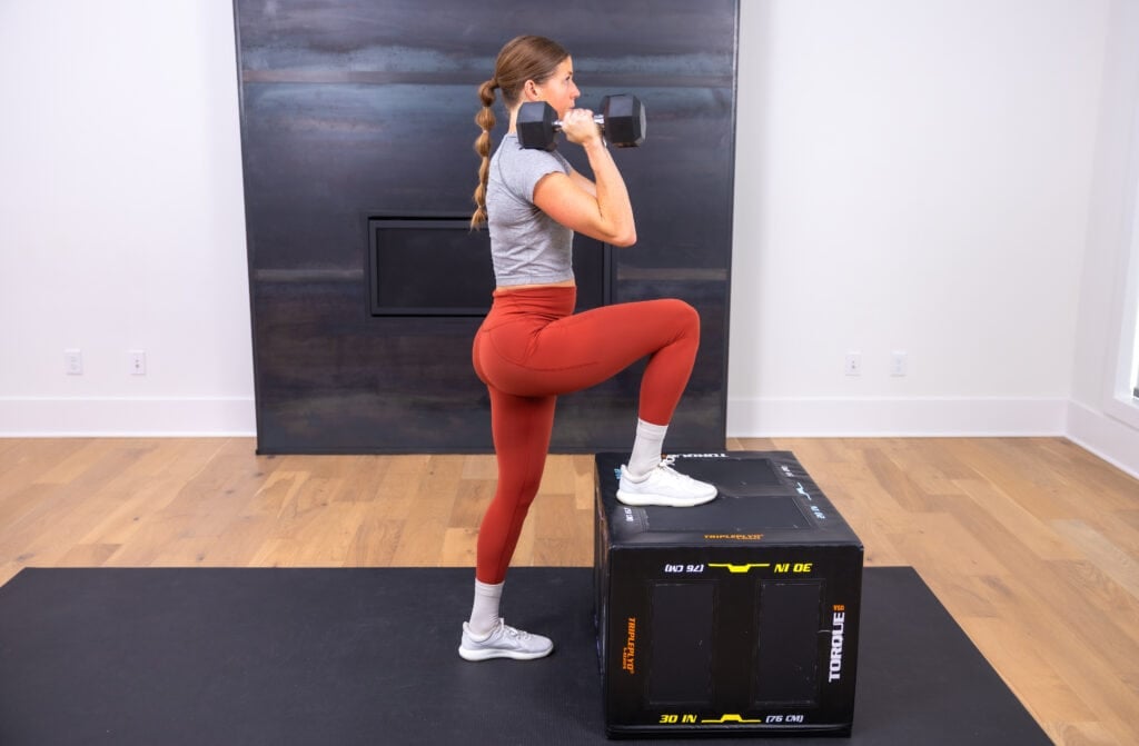 woman performing a single leg step up in a glute workout
