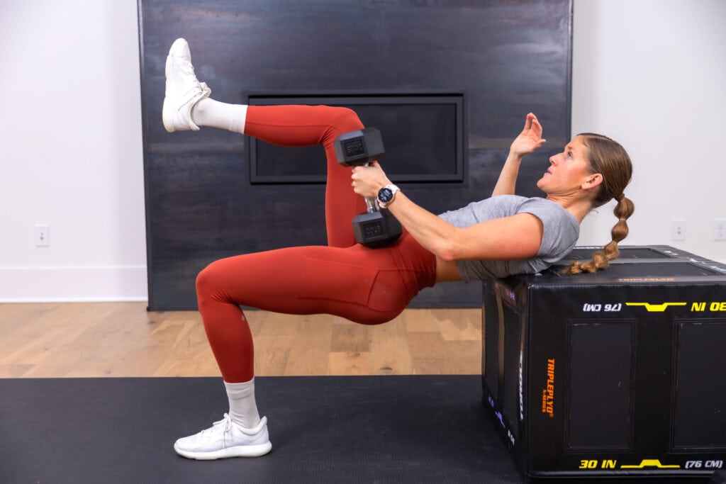 woman performing a single leg dumbbell hip thrust in a glute workout
