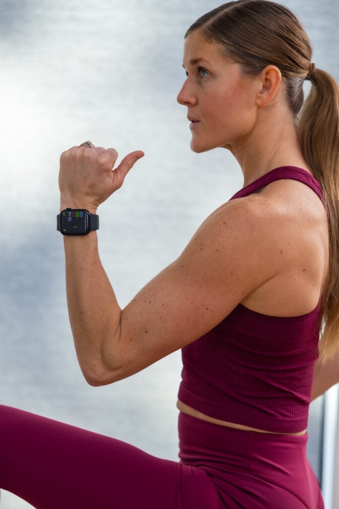Women doing high knees and wearing a black apple watch on her left wrist.