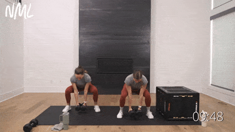 two women performing glute biased squats with dumbbells in a glute workout