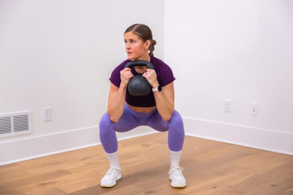woman holding kettlebell at her chest in a low squat position