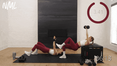 two women performing a single arm chest press with dumbbells as part of best dumbbell exercises