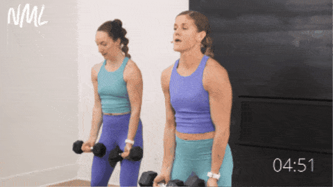 two women performing standing chest flys as part of dumbbell upper body workout