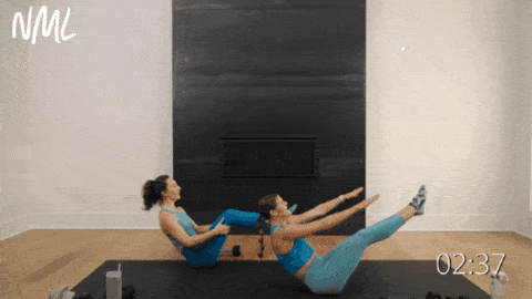 two women demonstrating barre exercise boat pose