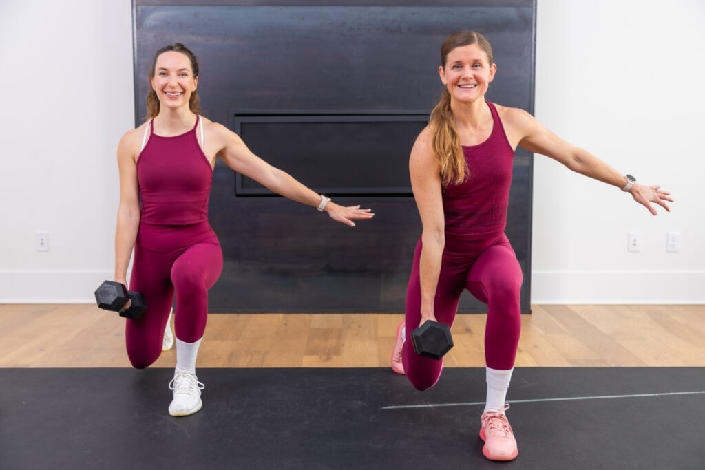 two women performing a reverse lunge as part of dumbbell workout