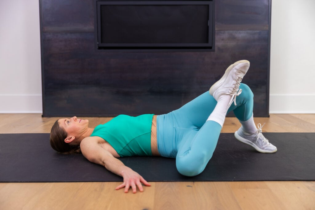 woman performing figure four stretch as example of si joint pain relief exercises