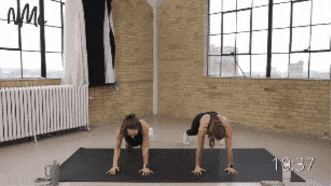 two women performing an army crawl and cross-body knee drive as part of full body bodyweight workout