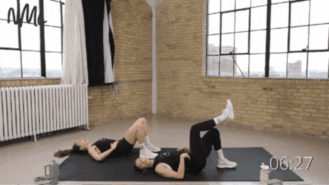 two women performing a single leg glute bridge as part of full body bodyweight workout