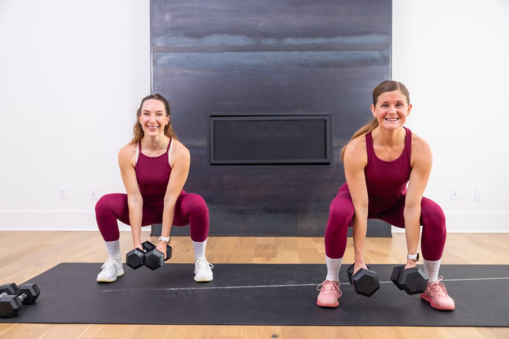 two women performing a dumbbell squat as part of full body dumbbell workout routine