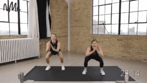 two women performing squat pulses with a squat jack as part of full body bodyweight workout