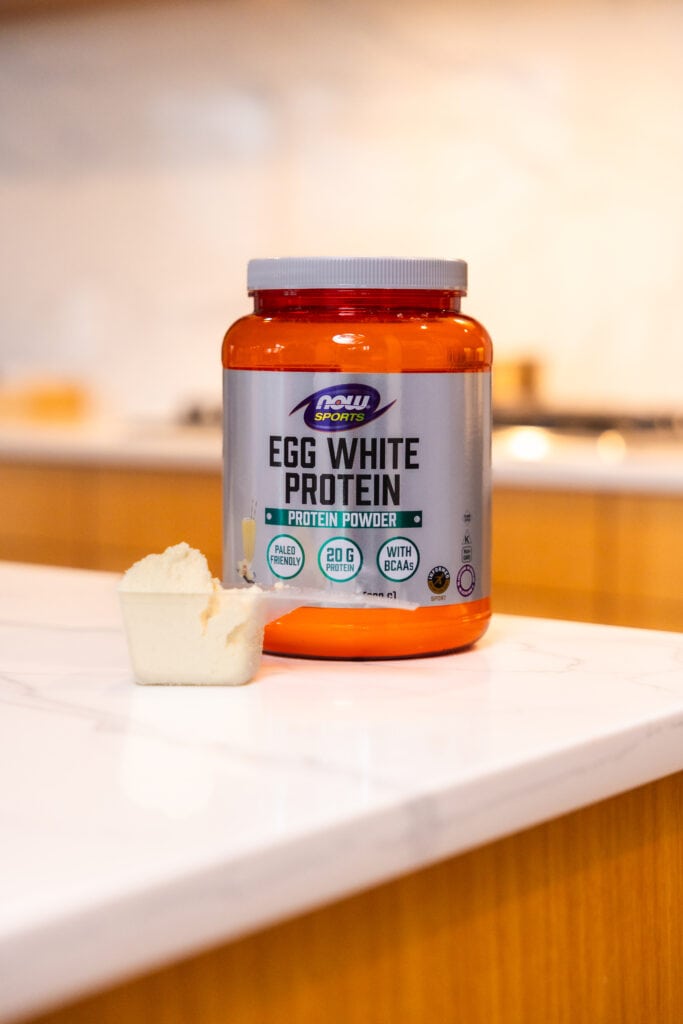 egg white protein powder on countertop with a scoop of vanilla protein as part of best protein powder