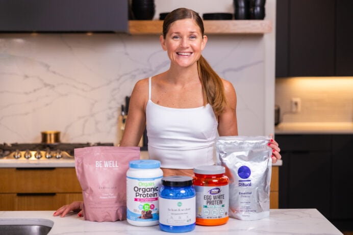 Lindsey with protein powders including BeWell Grass-fed protein powder, orgain organic protein powder, ora so lean and so clean protein powder, now foods egg white protein powder, ritual essentials protein