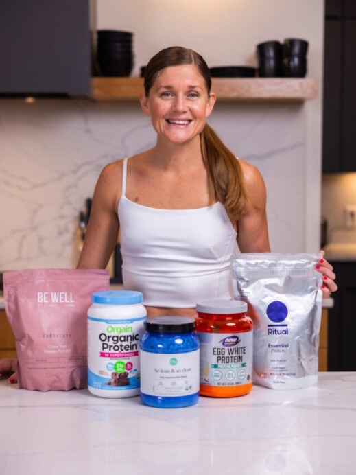 Lindsey with protein powders including BeWell Grass-fed protein powder, orgain organic protein powder, ora so lean and so clean protein powder, now foods egg white protein powder, ritual essentials protein