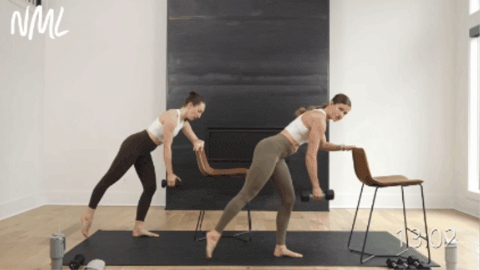 two women performing a rear leg lift as part of barre pilates class