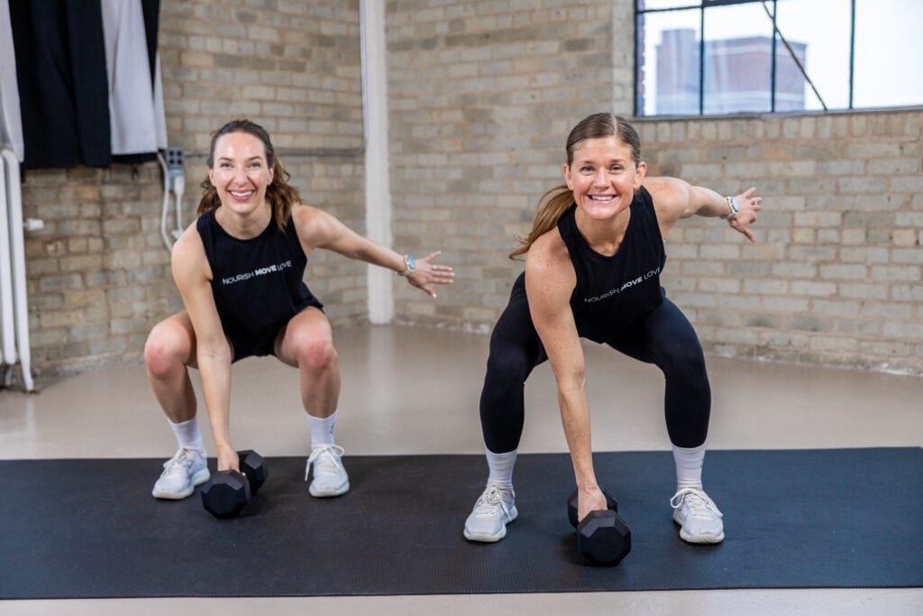 two women demonstrating a single dumbbell workout snatch exercise