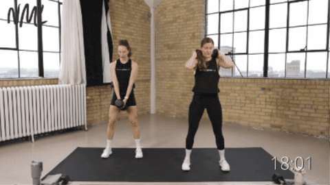 two women demonstrating a kang squat as part of a single dumbbell workout