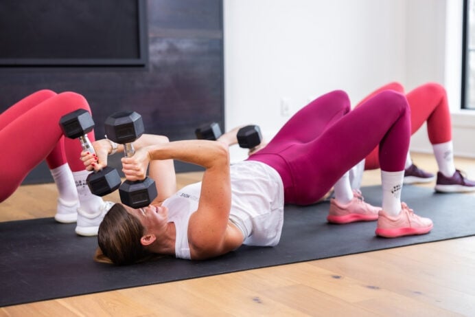 woman performing glute bridge with tricep extension as example of best hiit exercises for women