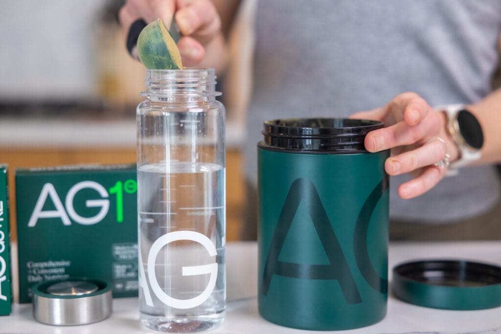 woman scooping AG1 into a water bottle.