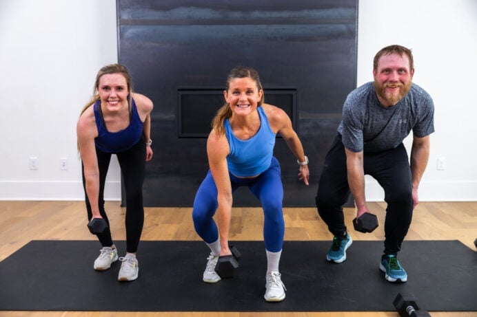 three people performing a low squat as part of total body workout