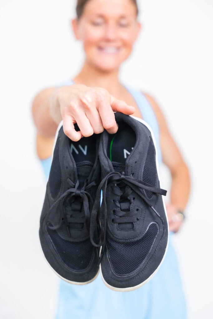 Women holding a pair of black barefoot shoes.