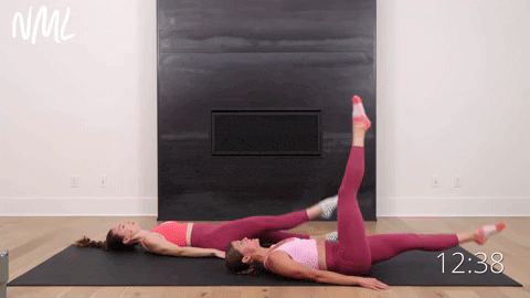 two women lying on their backs performing straight leg circles in a pilates ab workout
