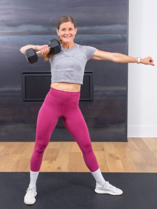 woman performing a single arm upright row in a strength and cardio workout
