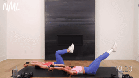 two women performing dumbbell crunches with an overhead pull