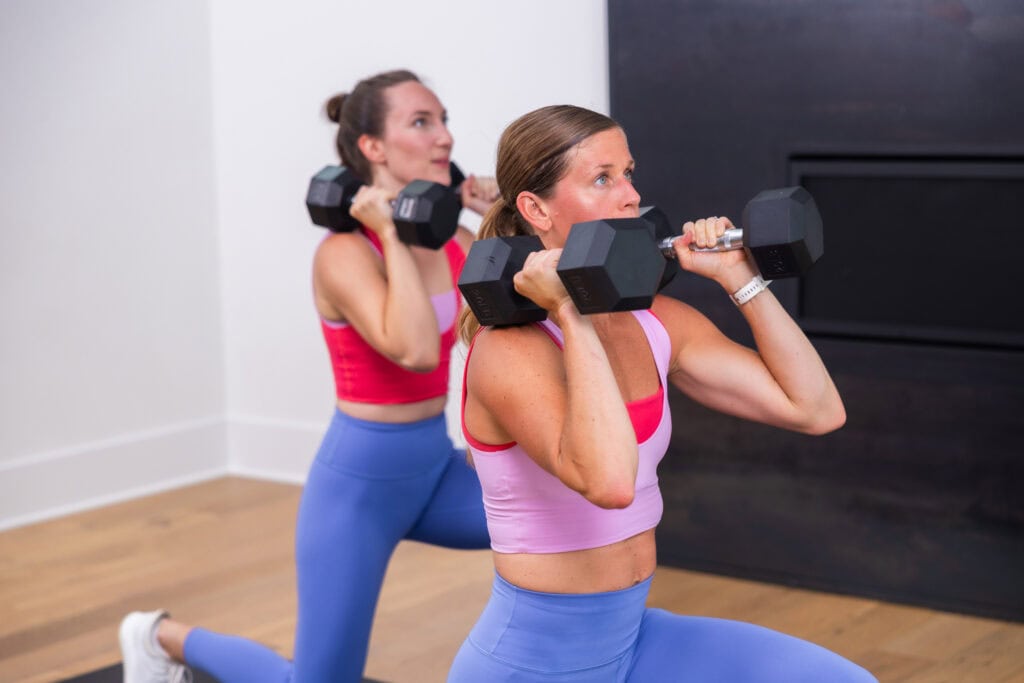 two women performing a dumbbell reverse lunge as part of hiit workout routine for women