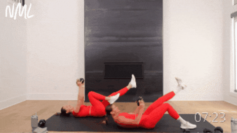 two women performing weighted sit ups as part of dumbbell hiit workout at home